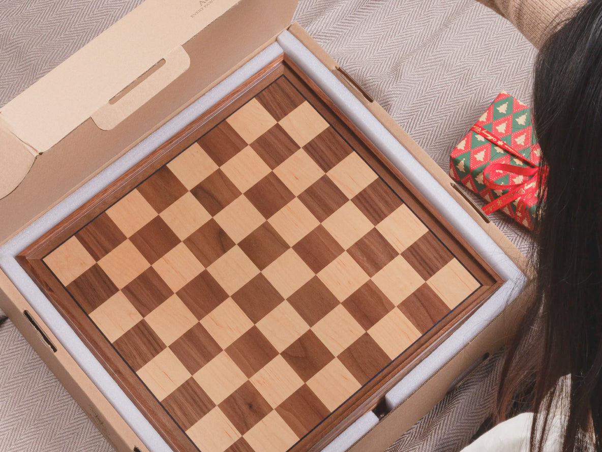 A person is opening a gift box, revealing a beautiful chess set inside.